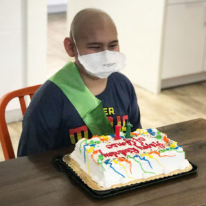 Boy smiles in the kitchen with his birthday cake