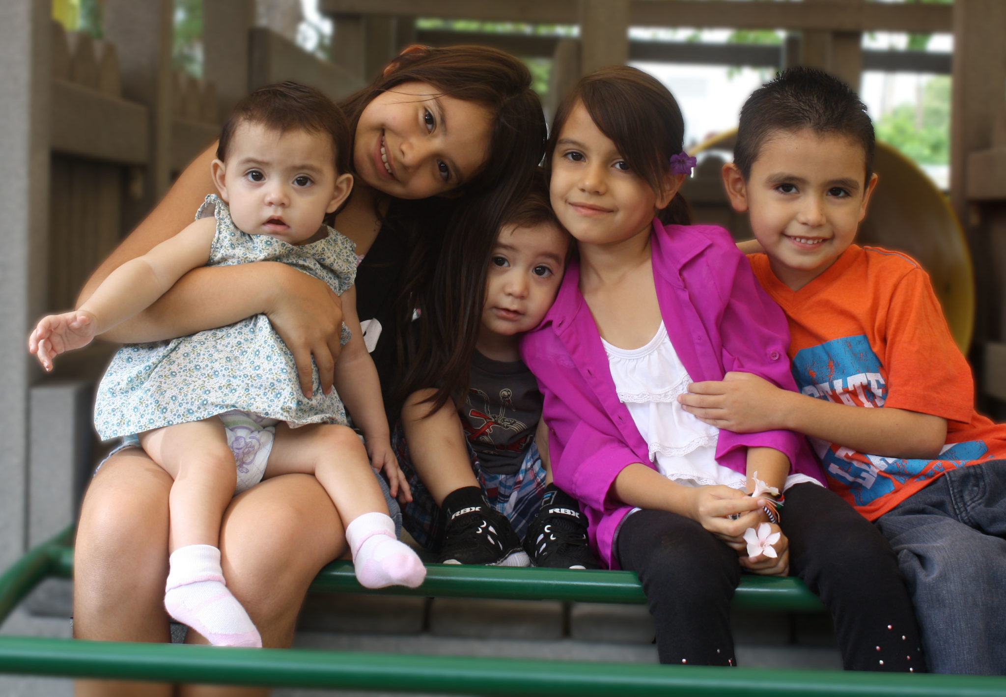 Four siblings posing in a hug on the RMHC playground