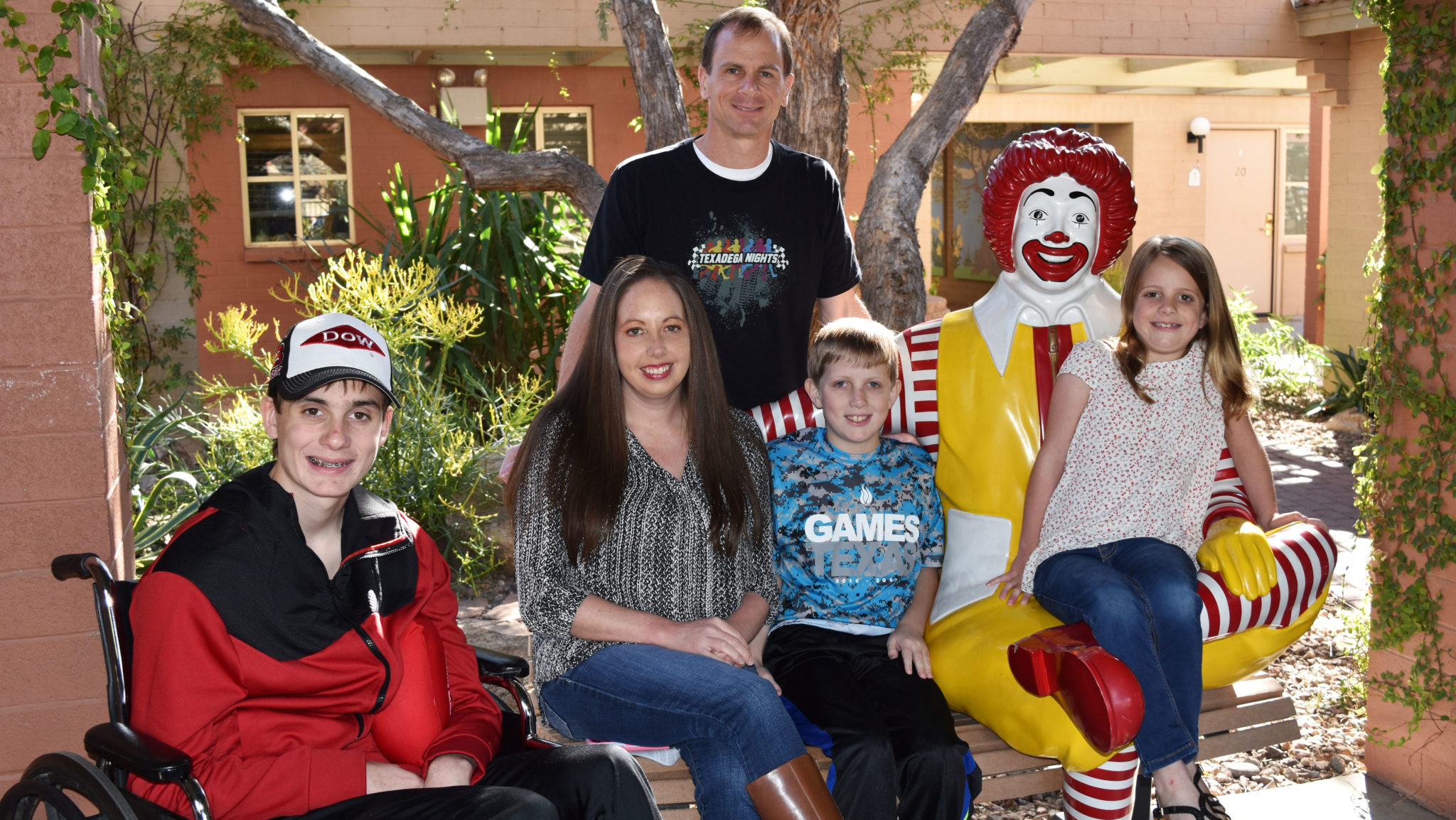 Family of 5 poses on the Ronald McDonald bench