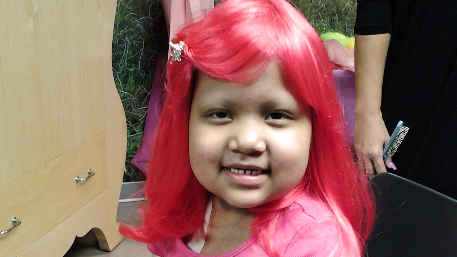 Girl with a bright pink wig poses for a photo