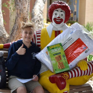 Tennage boy posing on the Ronald McDonald bench with donated items