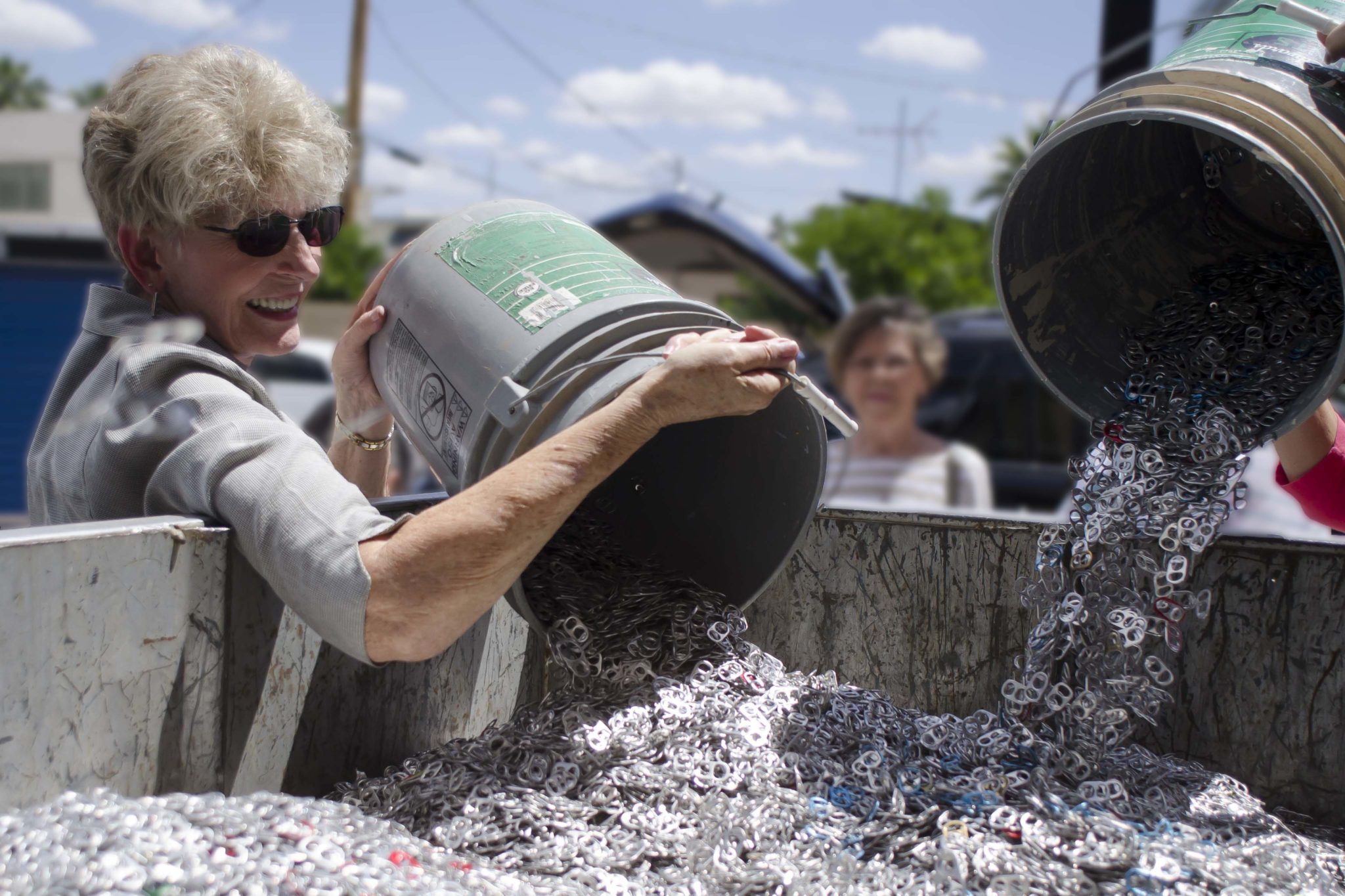 Woman pouring pop tabs into a large container