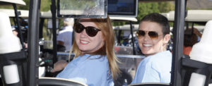 Two female volunteers pose in a golf cart
